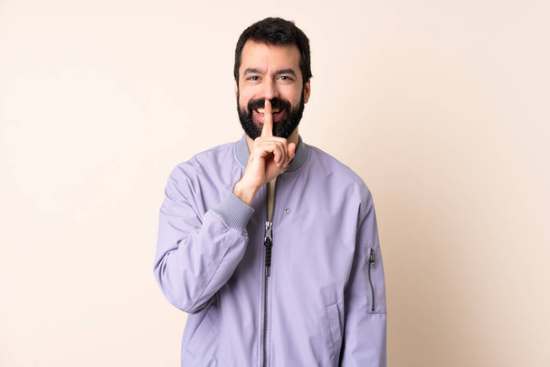 Caucasian man with beard wearing a jacket over isolated background showing a sign of silence gesture putting finger in mouth - Photo, Image