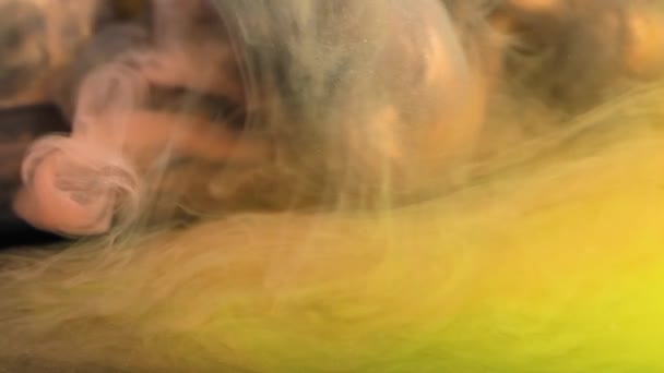 Een close-up weergave van de delicate werveling van rook boven een bed van levendige oranje en gele texturen. - Video