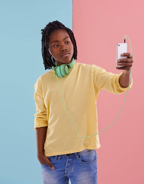 Έφηβος, αγόρι και selfie του μαθητή στο στούντιο με ακουστικά για να ακούτε μουσική στο γυμνάσιο με τη μόδα. Colorblock, mockup και post στα social media με αυτοπεποίθηση και υπερηφάνεια στην εικόνα προφίλ. - Φωτογραφία, εικόνα