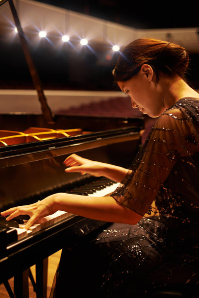 Music, concert and woman with piano on a stage for performance, entertainment and talent show. Musician, creative art and person practice playing instrument for melody, classical sound and symphony. - Photo, Image