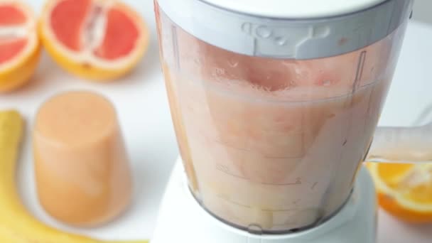 Pompelmoes, banaan en sinaasappel fruit smoothie maken, malen in blender, slow motion - Video