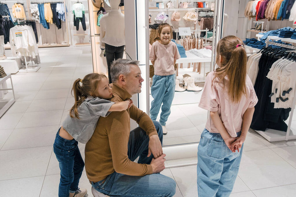 Padre elige ropa con hijas jóvenes en una boutique de moda - Foto, Imagen