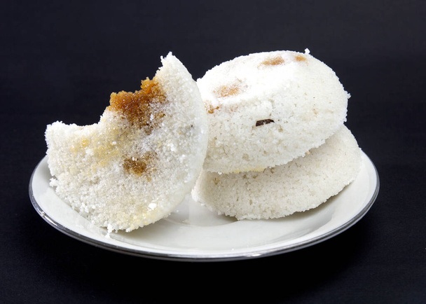 La torta di riso al vapore o Bhapa Pitha è un piatto tradizionale del Bangladesh. Torta di riso invernale su sfondo nero. morso o pitha rotto. Ingredienti sono riso in polvere, melassa, cocco, zucchero ecc. - Foto, immagini