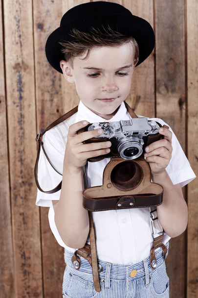 Boy looking at old camera - Foto, afbeelding