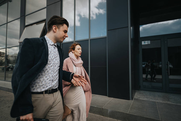 Két üzletember, egy férfi és egy nő, beszélgetnek, miközben sétálnak az üzleti negyedben.. - Fotó, kép