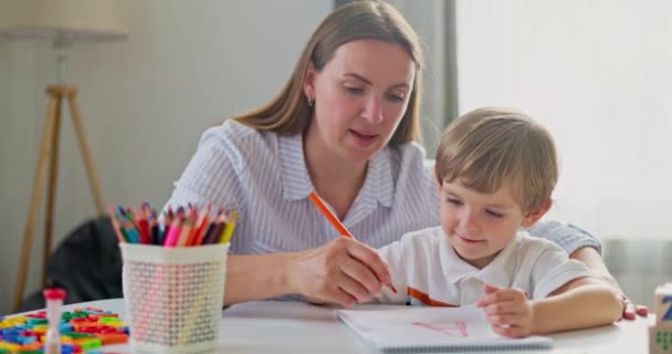 Vrouw en jonge jongen tekenen samen met gekleurde potloden. Het concept van thuisonderwijs. Hoge kwaliteit 4k beeldmateriaal - Video