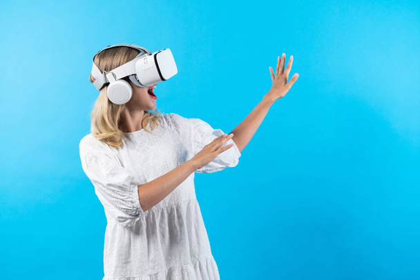 Skilled girl in pajamas excited with metaverse by using VR goggle at background. Caucasian woman surprised while looking around at futuristic view looking though visual reality goggles. Contraption. - Photo, Image