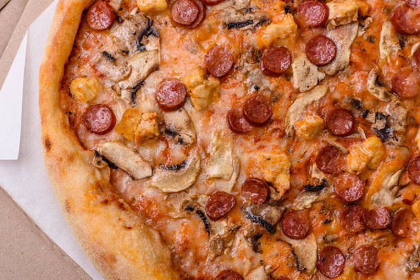 Νόστιμη πίτσα με λουκάνικο, τυρί, ντομάτες, αλάτι, μπαχαρικά και βότανα σε σκούρο σκυρόδεμα φόντο - Φωτογραφία, εικόνα