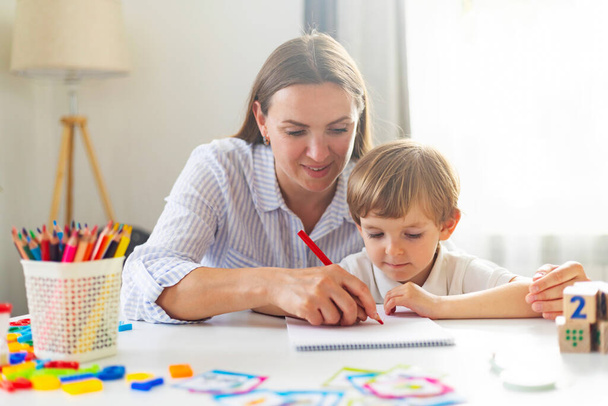 Kadın ve genç çocuk birlikte çiziyor, ev öğrenme konsepti. Tasarım ve tebrik kartları için kapalı alanda eğitim etkinliği. - Fotoğraf, Görsel