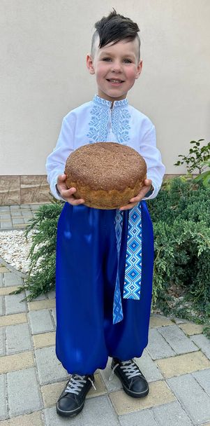 хлопчик у широких штанях тримає хліб - Фото, зображення