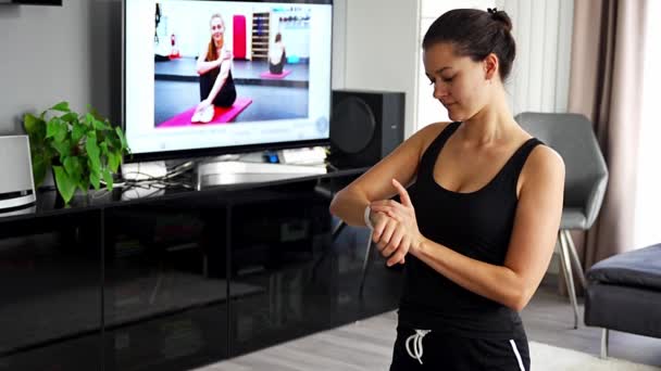 Młoda kobieta patrząc na fitness tracker wyświetlający tętno, kroki liczyć i spalone kalorie. Inteligentny zegarek na kobiecej dłoni, punkt widzenia, koncepcja utrzymania kondycji w domu. Wysokiej jakości materiał 4k - Materiał filmowy, wideo