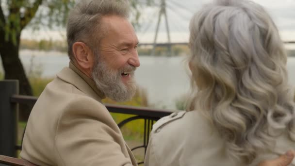 ハッピーファミリーシニア引退した白人60代男性笑顔話女性ロマンチックなデート週末に都市公園で陽気な喜びの老女笑うリラックスした愛のカップル屋外で - 映像、動画