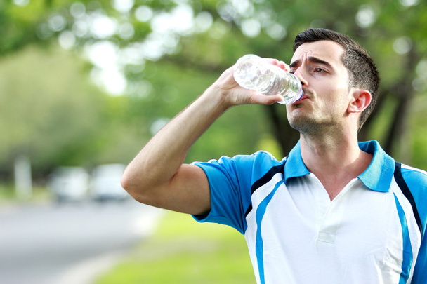 sporty male runner drinking mineral water at the break after run - Фото, зображення