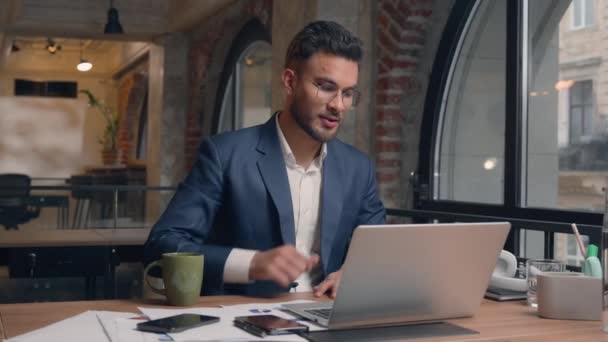 арабський втомлений чоловік бізнесмен закінчує робочий день комп'ютера закінчується закриттям свободи ноутбука щасливий усміхнений індійський бізнесмен в навушниках розслабляється слухати музику напій кава відпочинок насолоджуватися в офісі - Кадри, відео