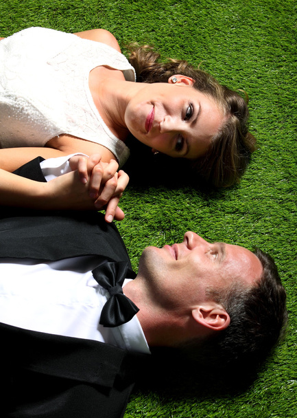 mariée et marié couché sur l'herbe tout en se tenant la main
 - Photo, image