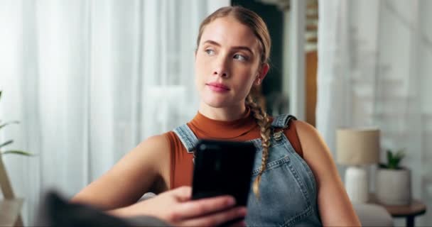 Woman, phone and sofa with thinking in home with texting, memory or ideas for contact in living room. Girl, smartphone and decision with web chat on couch in lounge with mobile app for social network. - Footage, Video
