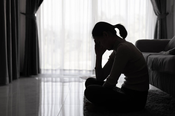 Bunalımlı kadın, depresyondaki genç kız silueti karanlık odada tek başına oturuyor. Siyah beyaz fotoğraf. - Fotoğraf, Görsel