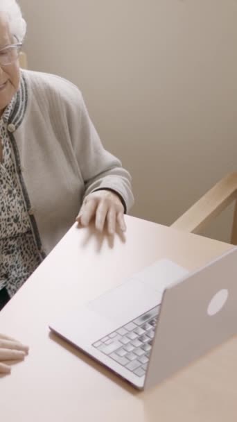 Video al rallentatore di due persone anziane sedute con il computer portatile durante una videochiamata da geriatria - Filmati, video