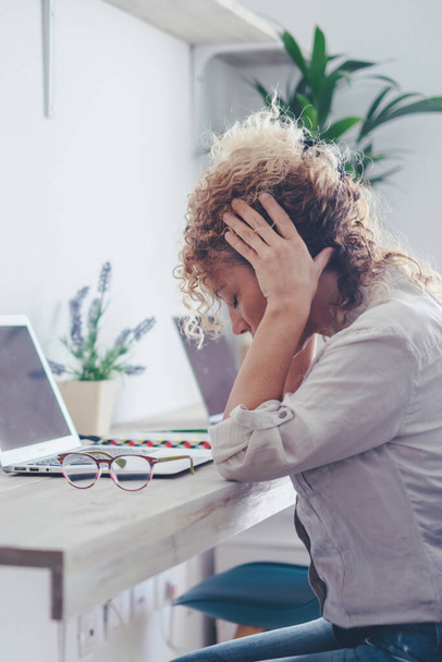 Niedobrze młoda kobieta rasy białej pracuje na komputerze w biurze domowym zdejmując okulary cierpi na migrenę lub ból głowy. Nieszczęśliwy zmęczony tysiącletnia kobieta zmaga się z zawrotami głowy lub niewyraźne widzenie za pomocą laptopa. - Zdjęcie, obraz