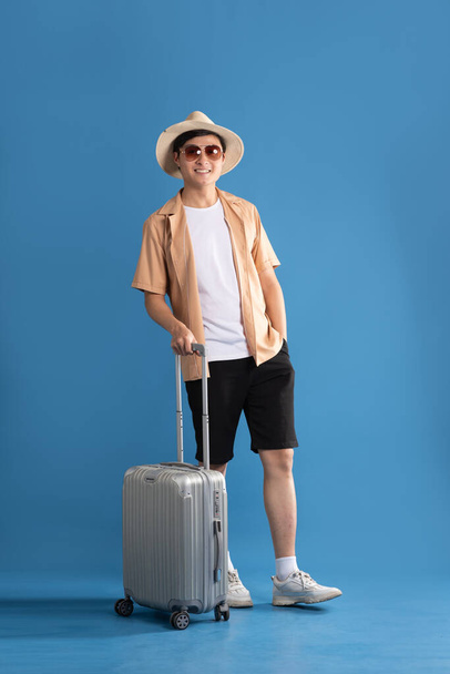 Портрет азиатского мужчины, позирующего на синем фоне, путешествующего летом - Фото, изображение