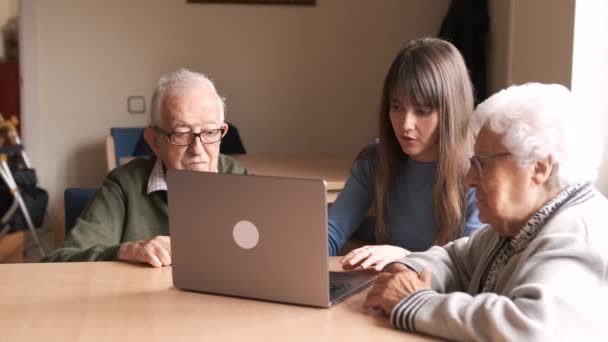 Медленное движение молодой женщины, сидящей за столом и обучающей пожилых людей нетбуку в доме престарелых - Кадры, видео