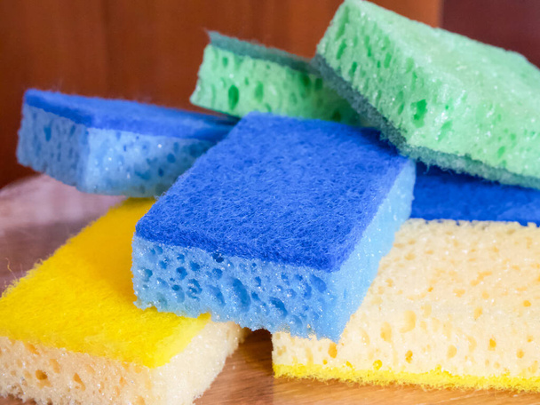 Esponjas limpiadoras vibrantes. Una pila de esponjas azules, amarillas y verdes. Usos para la limpieza de anuncios de productos, blogs domésticos. - Foto, Imagen