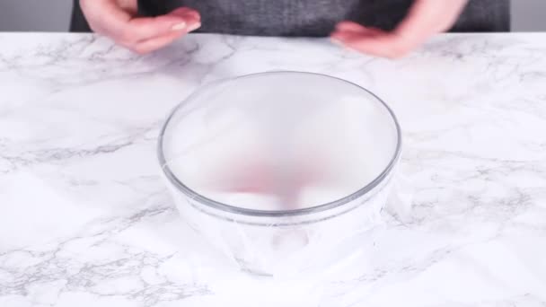 Aardbeien, vers gewassen en gedroogd, worden netjes opgeslagen in een glazen kom die is bekleed met een papieren handdoek en stevig bedekt met plastic omhulsel om versheid te behouden.. - Video