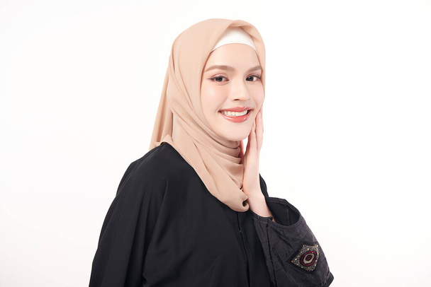 Schöne junge asiatische Muslimin trägt einen beigen Hijab auf weißem Hintergrund, Portrait of Arab Beauty. - Foto, Bild
