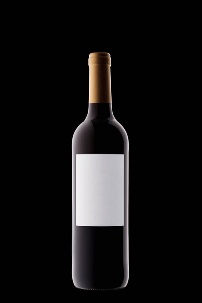 Láhev vína s bílým štítkem s krásnými zvýraznění na černém pozadí close-up - Fotografie, Obrázek