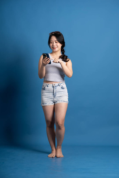Πορτρέτο του κοριτσιού από την Ασία ποζάρουν σε μπλε φόντο, ταξιδεύουν το καλοκαίρι - Φωτογραφία, εικόνα