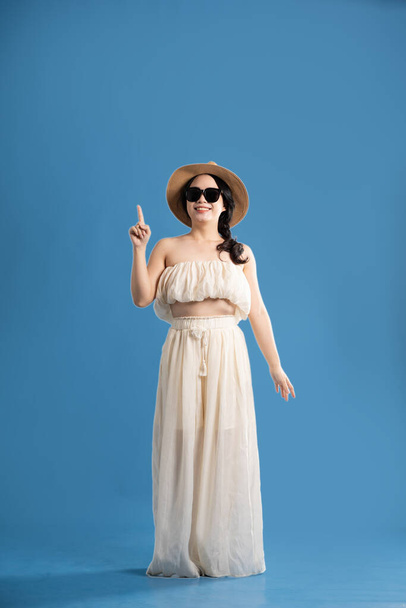 Retrato de chica asiática posando sobre fondo azul, viajando en verano - Foto, imagen