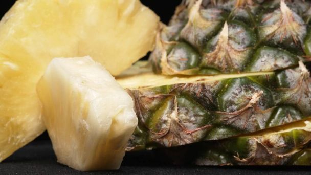 Lähikuva video tuoretta ananasta siivu kuori ananas insertti erotettu musta tausta. Karkea ja vahamainen kuori, ylpeillen kruunu piikikäs vihreät lehdet, Ruoka valokuvaus. Soveltuva. - Valokuva, kuva