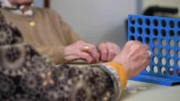 Femmes âgées jouant un jeu de stratégie traditionnel pour former 4 jetons rangée à la maison de soins infirmiers. Images 4k de haute qualité - Séquence, vidéo