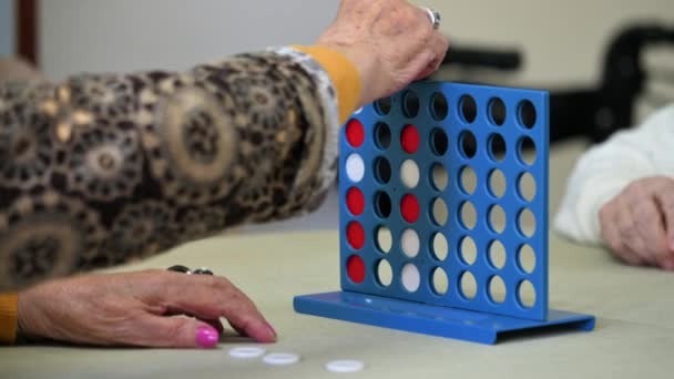 Oudere vrouwen spelen een traditioneel strategiespel om 4 chips rij te vormen in het verpleeghuis. Hoge kwaliteit 4k beeldmateriaal - Video