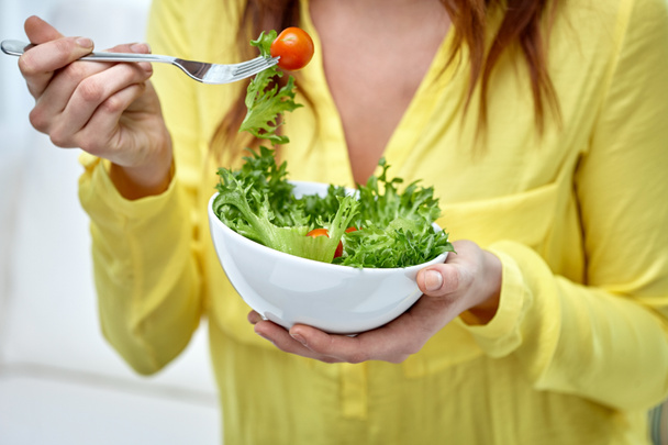 Close up van jonge vrouw salade eten thuis - Foto, afbeelding