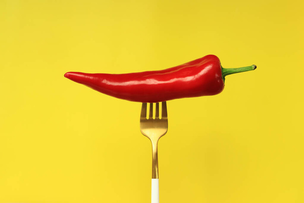 Pepe rosso su una forchetta, sfondo giallo. Peperoncino rosso caldo su fondo giallo. Concetto di cibo, verdure fresche e spezie - Foto, immagini