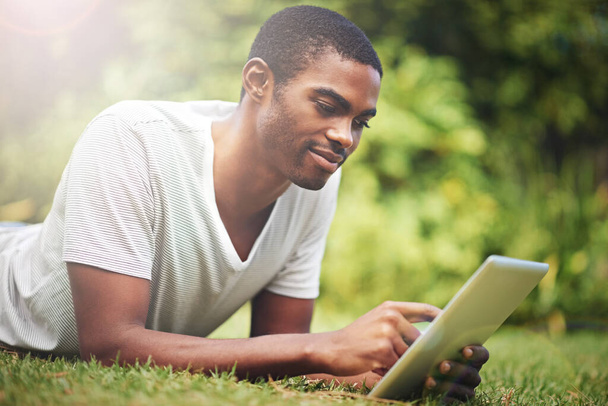 Relax, gelukkig en tablet met zwarte man op gras van de tuin voor onderzoek of informatie in de zomer. Technologie, internet en jongeren lezen online ebook op groen veld buiten in de achtertuin. - Foto, afbeelding