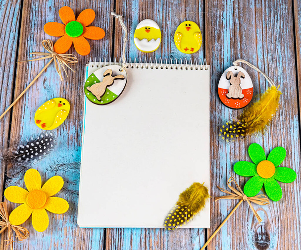 Osterkarte mit gelben und grünen Ostereiern, dekorativen Blumen, Federn auf einem hölzernen Hintergrund. Osterhintergrund, Platz für Text - Foto, Bild