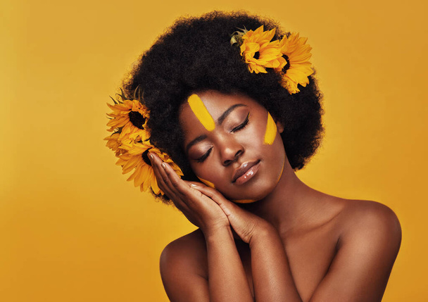 Black woman, studio and natural sunflowers for spring, nature skincare and rest with African model and afro. Selfcare, wellness for beauty with organic cosmetics, dermatology on yellow background. - Photo, Image