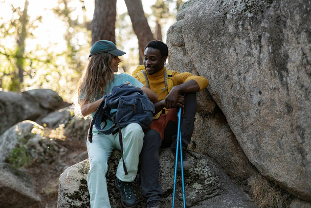 A couple enjoys a close, affectionate moment on the rocky terrain, surrounded by the tranquil beauty of the forest. - Photo, Image