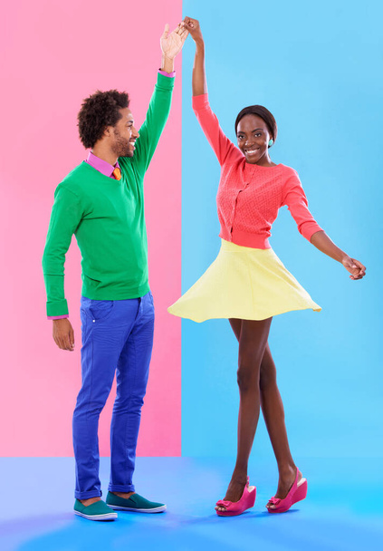 Happy, dance and couple in studio with fashion and holding hands, spinning and creative portrait. African, woman and man together with colorful retro style, unique clothes or moving with support. - Photo, Image