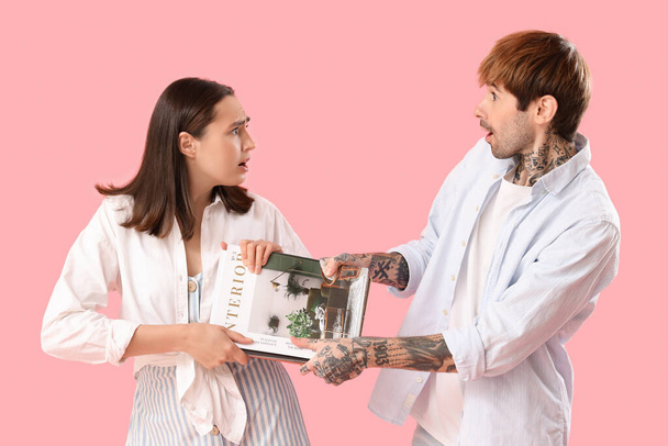 Нещасна молода пара бере журнал на рожевому фоні - Фото, зображення