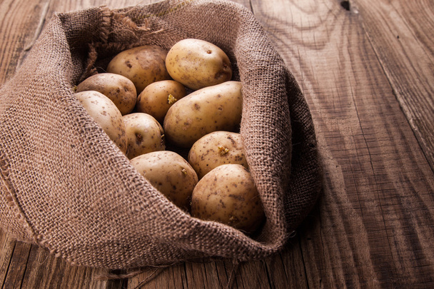 Harvest potatoes in burlap sack - Foto, afbeelding
