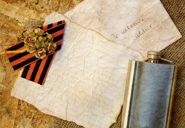 Flores de papel, cinta de San Jorge, frasco de cadera sobre un saco
 - Foto, Imagen