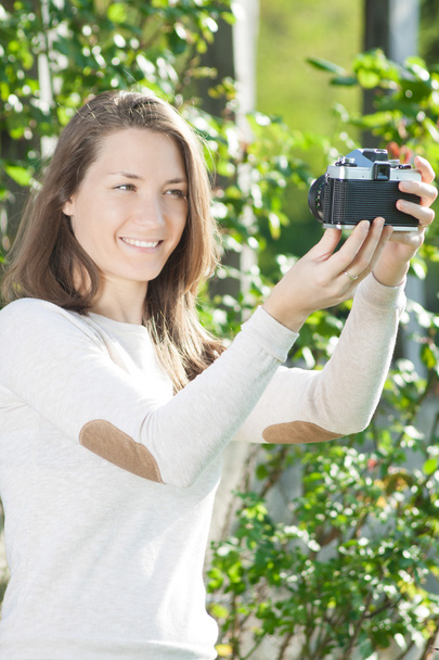 Szczęśliwa młoda kobieta fotograf za pomocą starego aparatu - Zdjęcie, obraz