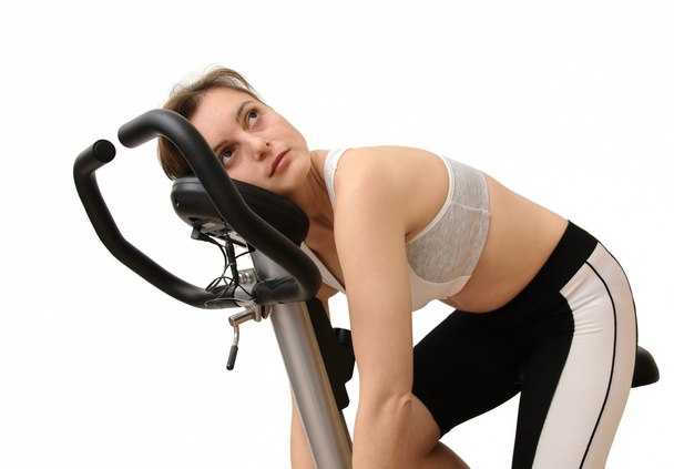 Isolated tired young woman siting on spinning bicycle - Foto, Imagen