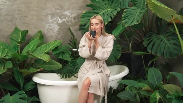 Tropical and exotic spa garden with bathtub in modern hotel or resort with young woman in bathrobe drink coffee, enjoy leisure and wellness lifestyle surround by lush greenery foliage. Blithe - Footage, Video