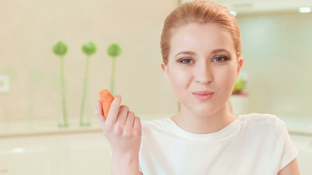 νεαρή γυναίκα τρώει καρότο. Βιολογικά τρόφιμα - Πλάνα, βίντεο