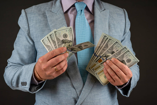 zakenman dragen pak tonen ons dollar geld bankbiljetten geïsoleerd op zwart. Financieel concept - Foto, afbeelding