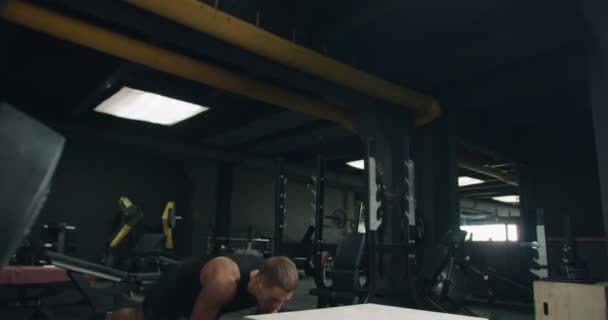 Soustředěný mladý samec sportovec provádějící box skoky v dobře vybavené tělocvičně, demonstrující silný fitness rutinu a sílu. Mladý muž v intenzivní cvičení sezení v moderní tělocvičně - Záběry, video